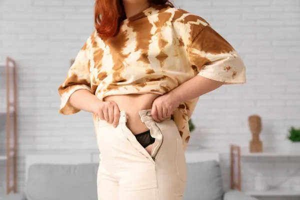 Image of woman trying to do her trousers up after pregnancy weight gain Lincolnshire